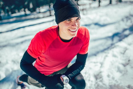 Man sportsman taking break from running in extreme snow conditions