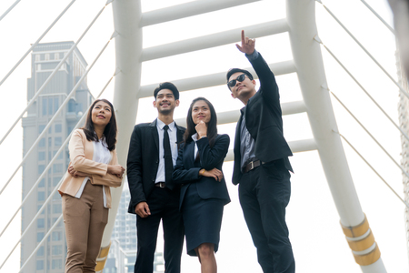 Handsome businessman standing pointing forward let a group of businessmen see something in modern city