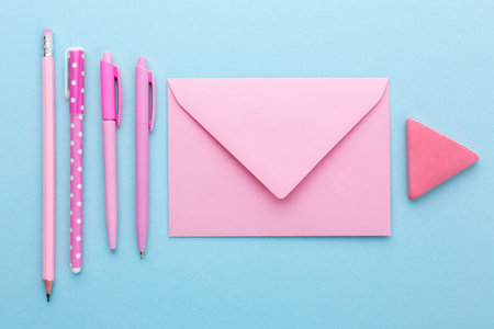 Top view of pink envelopes pens and eraser on blue background