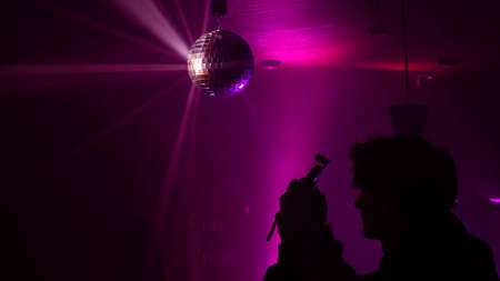 Party atmosphere with disco ball light beams reflecting from a disco ball Stock Photo