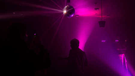 Party atmosphere with disco ball light beams reflecting from a disco ball
