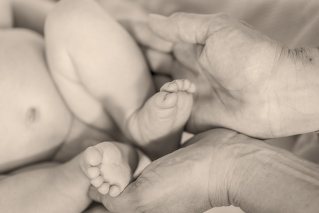 Newborn baby boy feet in mother s hands monochrome shoot