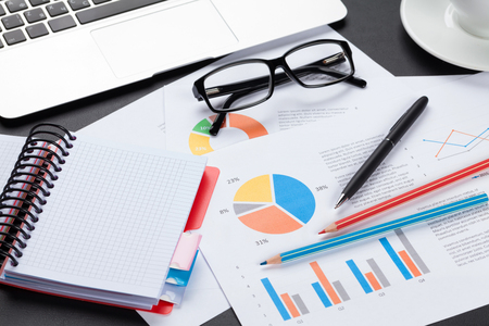 Office leather desk table with laptop coffee cup notepad and reports Stock Photo