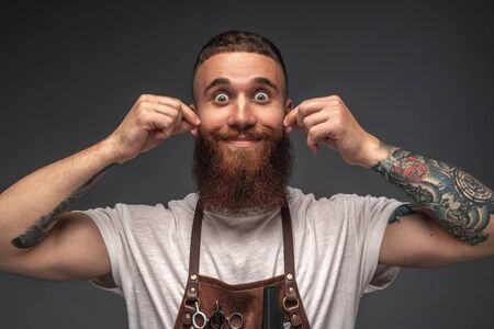 Divertido peluquero torciendo el bigote y sonriendo