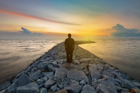 Silhouette of a man near sea watching a golden sunset Stock Photo