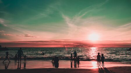 Silhouettes of people on the beach at sunset city residents are enjoying a weekend by the sea dramatic sky and clouds