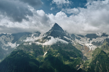Sharp mountain peak landscape with cloudy sky rocky ranges and peaks with glaciers and snow fields wild nature view belalakaya dombay caucasus