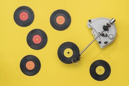 Tocadiscos antiguos con discos de vinilo multicolores sobre un fondo amarillo. Técnica retro para tocar música.