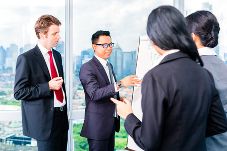 Asian businesspeople looking at flipchart