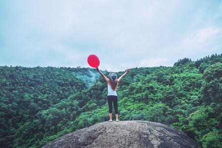 Asian women travel relax in the holiday standing hands on a rocky cliff wild nature wood on the mountain