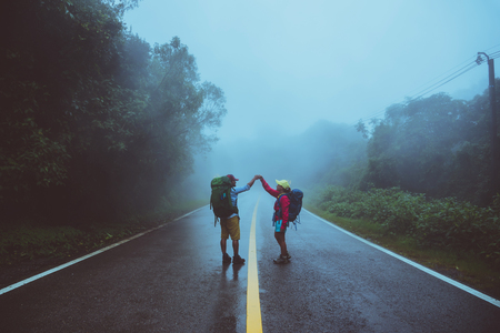 Lover asian man and asian women travel nature walk on the road route traveling nature happily amid the mist rainy in the rainy season