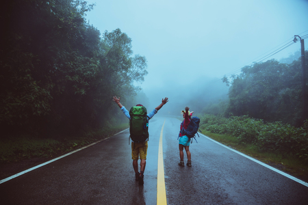 Lover asian man and asian women travel nature walk on the road route traveling nature happily amid the mist rainy in the rainy season