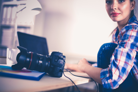 Female photographer sitting on the desk with laptop female photographer