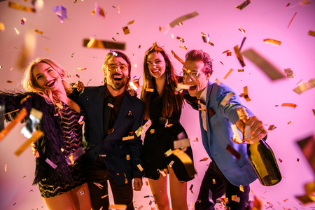 amigos emocionados con una botella de champán divirtiéndose en una fiesta con confeti, en rosa
