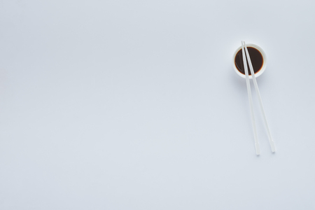 Top view of soy sauce in bowl and chopsticks isolated on white background