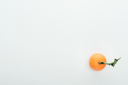 Bright ripe orange tangerine with green leaves on white background with copy space