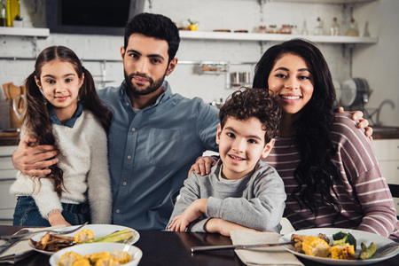 alegre familia latina sonriendo mientras mira la cámara durante el almuerzo Foto de archivo