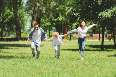 familia emocionada tomándose de la mano y corriendo en el parque durante el día
