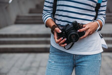 Cropped view of woman in casual holding digital camera