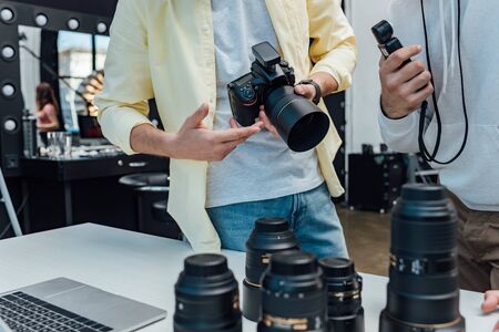 Selective focus of art director standing with photographer near photo lenses