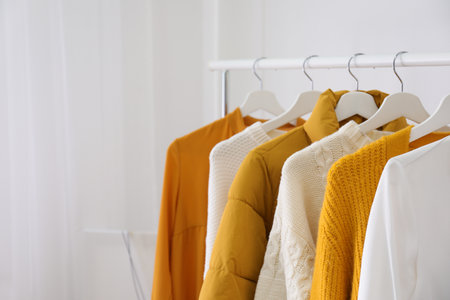 Rack with stylish warm clothes indoors closeup space for text