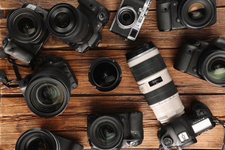 Modern cameras on wooden table flat lay