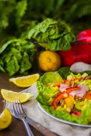 Bowl of fresh salad with vegetables and greens on wooden table