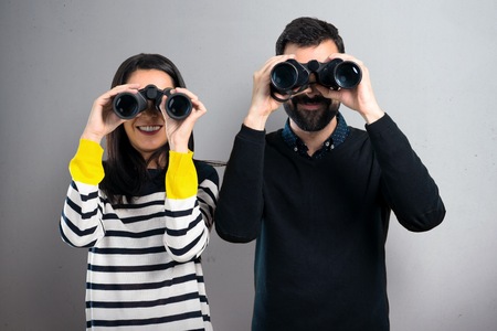 Couple with binoculars on grey background