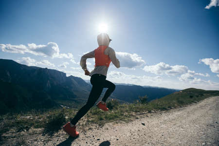 Young woman ultramarathon runner running at mountain top Stock Photo