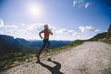 Woman trail runner running on mountain top