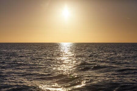 Sol poniente sobre el océano reflejado en el agua, fondo natural.