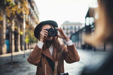 Outdoor glimlachende lifestyle portret van mooie jonge vrouw hebben plezier in de zon stad Europa herfst met camera reizen foto van fotograaf Het maken van foto's in glazen en hoed met vriendinnen Stockfoto
