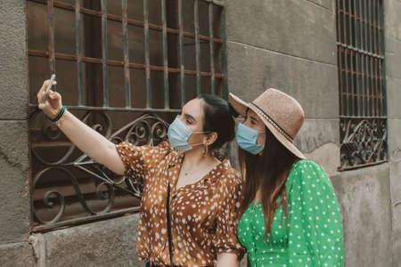 Dos amigas con máscara en la nueva normalidad tomando selfie