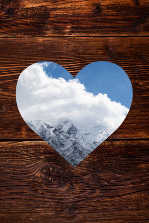 Austrian alps in heart shape window on vintage wooden background snow covered mountain winter