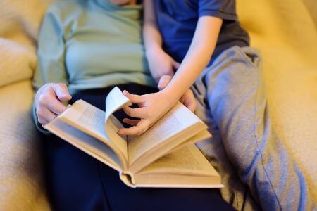 Elderly grandmother and little grandchild reading a book at home grandma and grandson quality family time