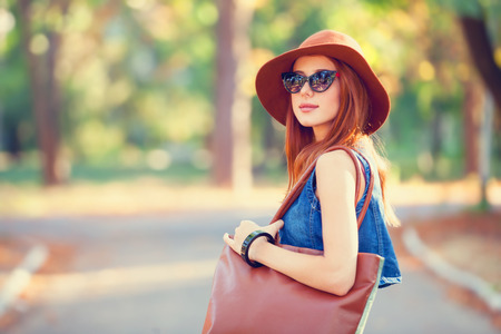 Beautiful redhead girl with bag in the park