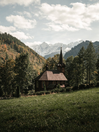 Die Holzkirche St. anna in tatranska javorina - slowakei mit wunderschönen schneebedeckten bergen im hintergrund. vertikales Landschaftsfoto einer Holzkapelle unter den Hügeln mit grüner Grasumgebung.