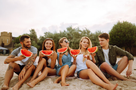 Young friends relaxing on the beach and eating watermelon people summer lifestyle Foto de archivo