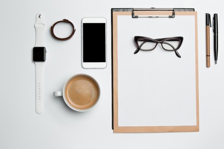 Office desk table with cup supplies phone on white background