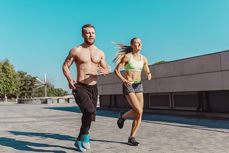 Pretty sporty woman and man jogging at city