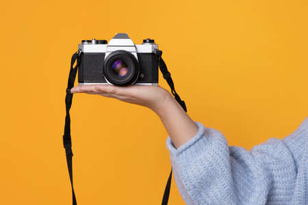 Studio photo with orange background of a woman s hand holding a digital camera