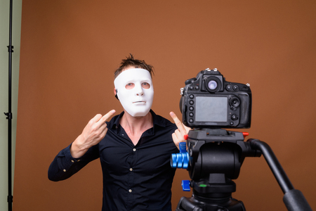 Jonge man dragen masker tijdens vloggen en tonen middelvinger