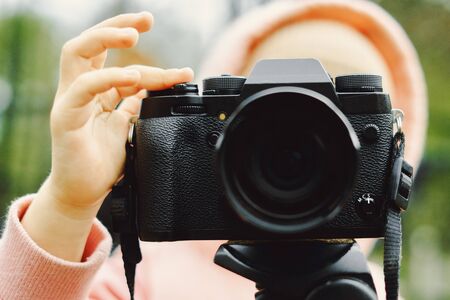 Girl shoots on a vintage film camera close up on the background of forest