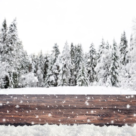 Blurred winter background with snow covered forest and shabby table Stock Photo