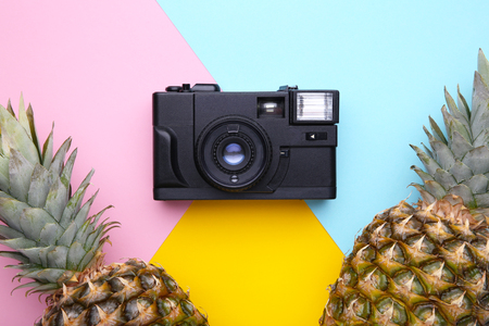 Ripe pineapples with camera on a colorful background Stock Photo