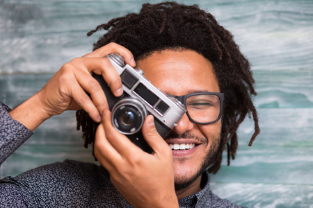 Happy hipster man smiling with toy camera on rustic backgorund Stock Photo