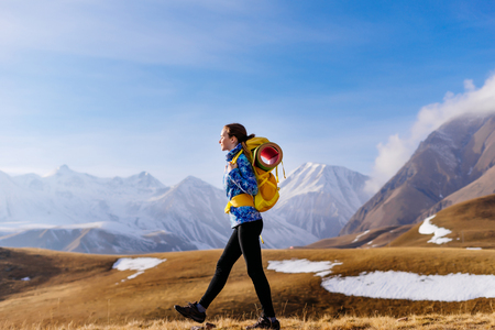 Active young girl goes on a campaign in the caucasus mountains with a backpack and tent