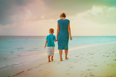 madre e hijo caminando en la playa puesta de sol Foto de archivo