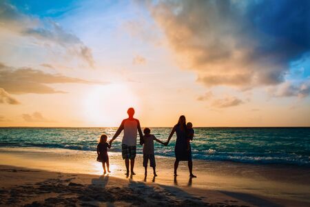 familia feliz con los niños del árbol caminan en la playa de la puesta del sol