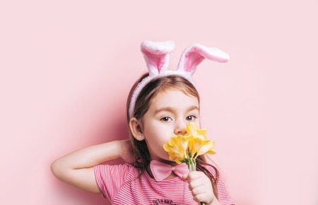 Niña linda con orejas de conejo sobre fondo rosa.